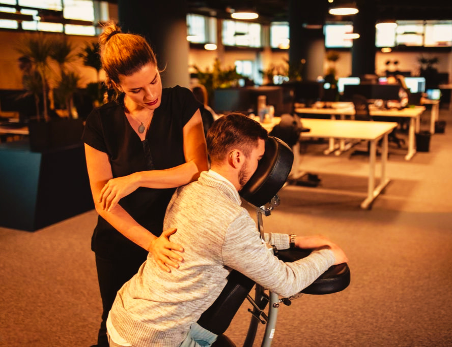 Licensed massage therapist providing onsite chair massage in a modern office